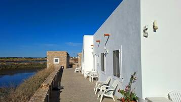 A coastal building with a stone pathway leading to outdoor seating.