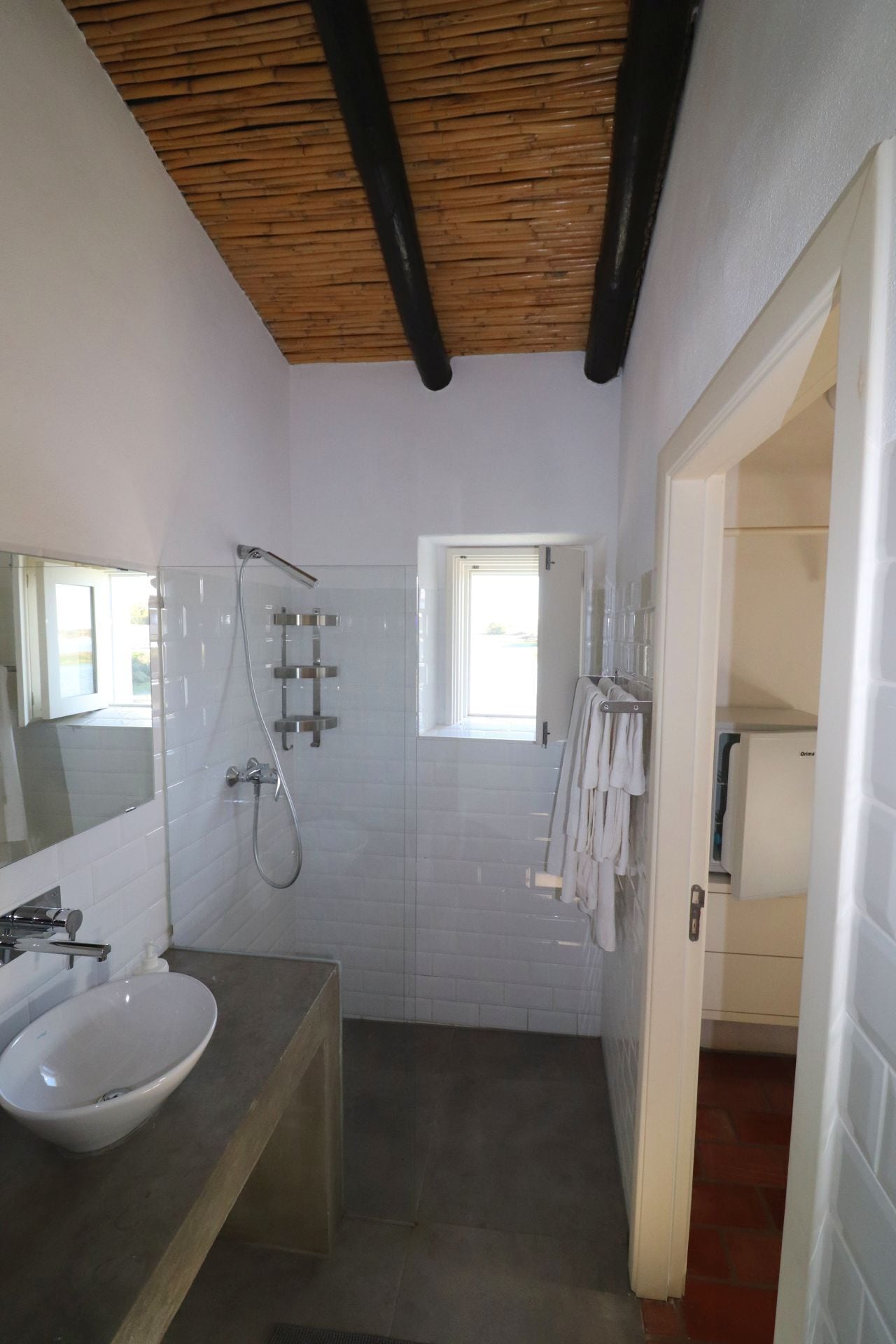 Un baño con lavamanos blanco, ducha y perchero.