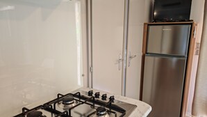 A kitchen with a gas stove, a stainless steel refrigerator, and a television on top of the fridge. - Mobile-home Camping L'ardecho [Magnolia] (Saint-Lager-Bressac)