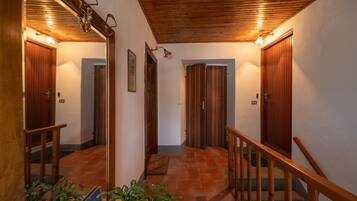Un pasillo con puertas de madera, una escalera de madera y un suelo de baldosas.