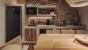 A compact kitchen with a refrigerator, microwave, and built-in appliances. There is a dining area with a wooden table and chairs. - Son's House - La Santisima Cartagena (Cartagena de Indias)