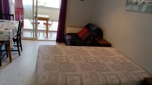 A bedroom with a bed, a table, and chairs. - Studio for 2, fully equipped, loggia, park view, city center. (Balaruc-les-Bains)
