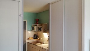 A compact kitchen with a sink, two small appliances, and a red coffee maker on the countertop. - Studio for 2, fully equipped, loggia, park view, city center. (Balaruc-les-Bains)