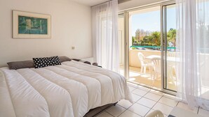 Un dormitorio con cama, un cuadro y un balcón con mesa y sillas.