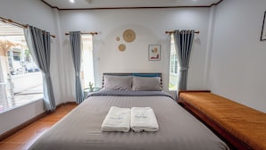 A neatly made bed with towels, a wooden bench, and a view of the outside. - Halo Sea Kohlarn (Koh Lan)