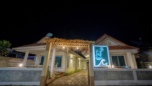 A hotel entrance with a thatched roof, a neon sign, and a paved pathway leading to the door. - Halo Sea Kohlarn (Koh Lan)