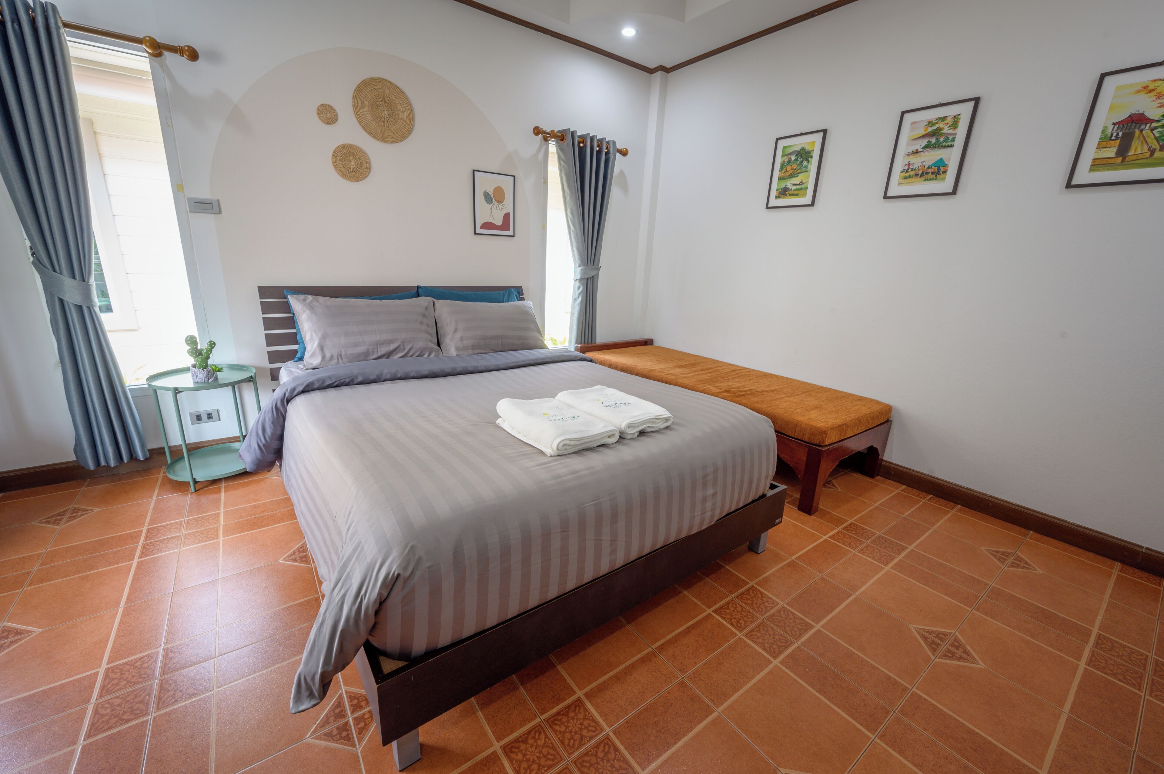 Une chambre à coucher avec un lit, une table de chevet, un banc et une petite table sur laquelle est posée une plante.