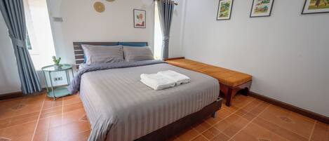 Une chambre à coucher avec un lit, une table de chevet, un banc et une petite table sur laquelle est posée une plante.