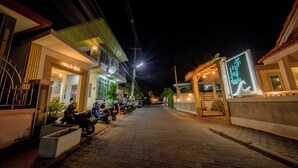 A nighttime street view with a row of parked motorcycles, a building with a neon sign, and a well-lit entrance. - Halo Sea Kohlarn (Koh Lan)