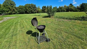 A grassy field with a barbecue grill in the center. - Apartment 'By B2' with Wi-Fi (Thüngen)