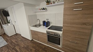 A compact kitchen with a built-in oven, a sink, and a countertop with a coffee maker. - Apartment 'By B2' with Wi-Fi (Thüngen)