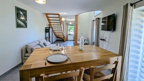 A dining area with a wooden table, chairs, and a staircase leading to an upper level. - Gîte le Saule between Épinal and Saint-Dié with Wi-Fi (Nonzeville)