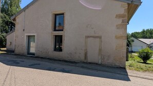 A single-story building with a flat roof, a small window, and a garage door. - Gîte le Saule between Épinal and Saint-Dié with Wi-Fi (Nonzeville)