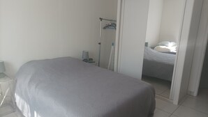 Une chambre à coucher avec un grand lit, une table de chevet, une lampe, une armoire et un miroir.