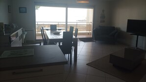 Un salon comprenant un coin repas, un canapé, un téléviseur et un balcon avec vue.