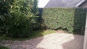 A paved patio area with a tiled floor, surrounded by dense green foliage and a hedge. - 50m² House near beach in Le Croisic with parking (Le Croisic)