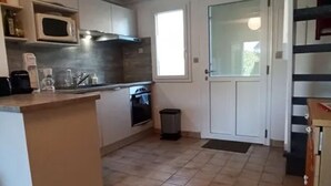 A kitchen with a microwave, oven, and sink. There is a window and a door with a doormat. - 50m² House near beach in Le Croisic with parking (Le Croisic)