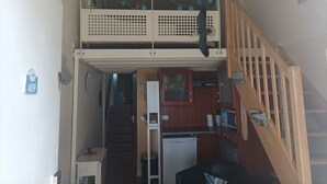Een huis met twee verdiepingen, een keuken op de begane grond en een balkon op de bovenverdieping.