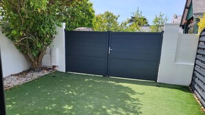 A fenced backyard with artificial green turf, a tree, and a white wall. - Quiet house 4-6 pers. near Le Croisic port (Le Croisic)