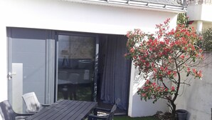 A patio with a table and chairs, a sliding glass door, and a small tree with red flowers. - Quiet house 4-6 pers. near Le Croisic port (Le Croisic)
