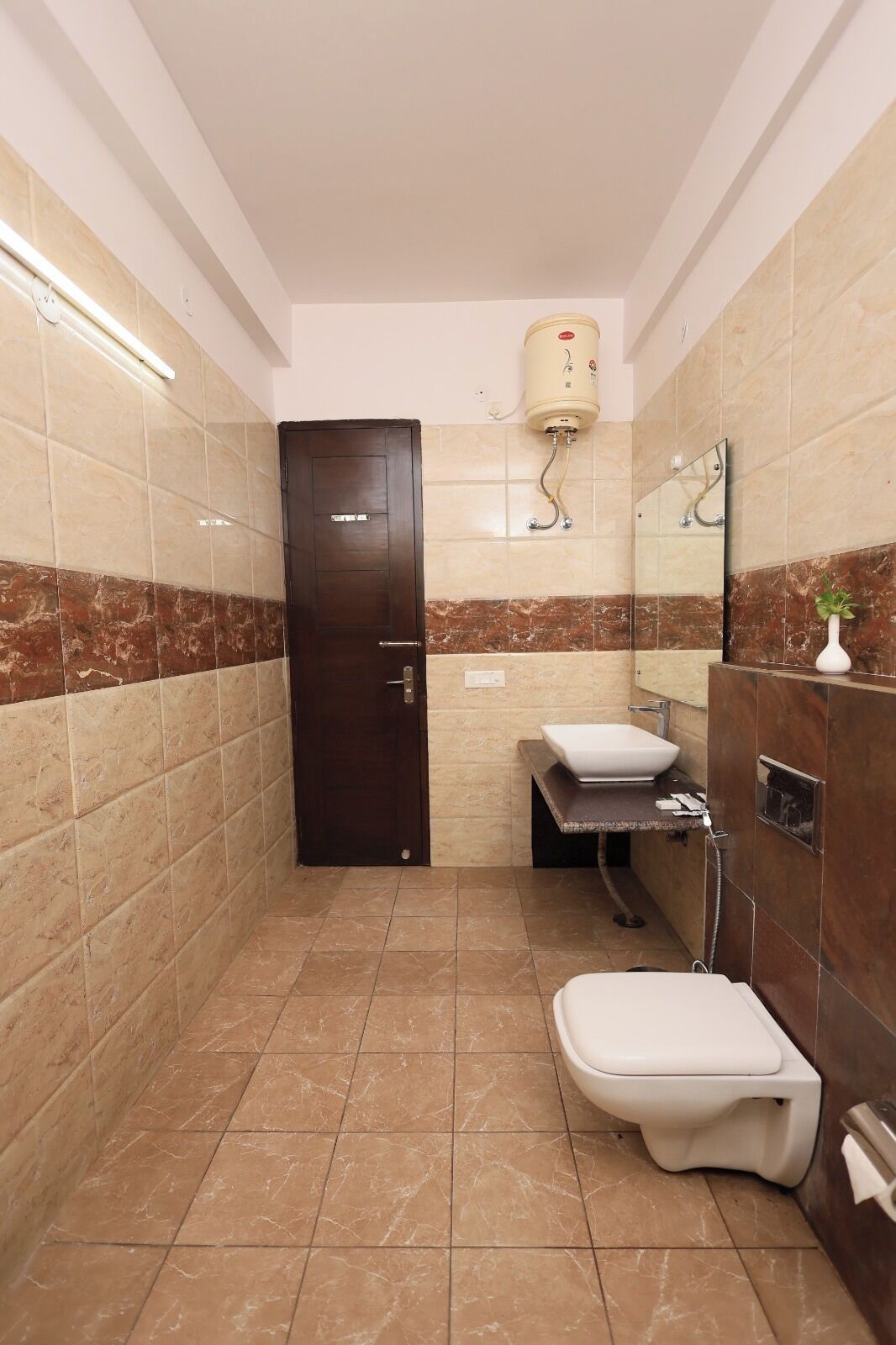 A bathroom with a toilet, sink, and shower area, featuring tiled walls and a marble floor.