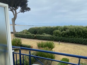 Ein Balkon mit Blick auf einen angelegten Garten und das Meer.
