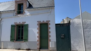 Un edificio de dos pisos con fachada blanca, contraventanas verdes y una puerta verde.