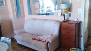 Ein Zimmer mit einem beigen Sofa, einem Holzschrank und einem Spiegel an der Wand.