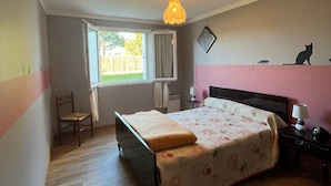 Un dormitorio con cama, una silla, una mesita de noche, una lámpara, una ventana y una pared con siluetas de animales.