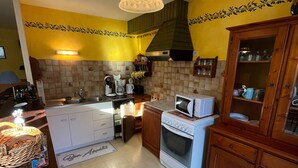 Cocina compacta con armarios blancos, un microondas, una estufa y un lavabo.