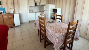 Una cucina compatta con zona pranzo, dotata di un piccolo frigorifero, forno a microonde e lavello.
