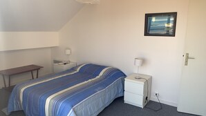 Une chambre à coucher avec un lit, une table de chevet, une lampe et une porte.