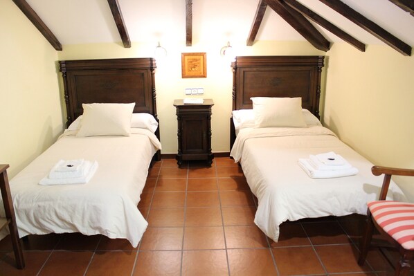 A room with two beds, a small table, and a chair. - 3 Cabras Perdidas (Arbo)