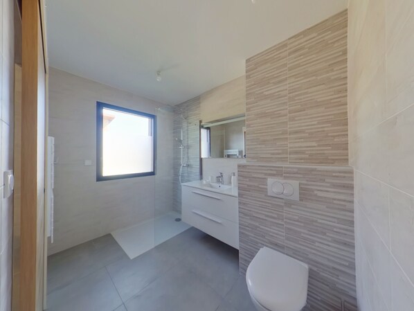 A modern bathroom with a shower, toilet, and vanity. - Spacious Villa Romane for 12, near slopes in Les Rousses (Les Rousses)