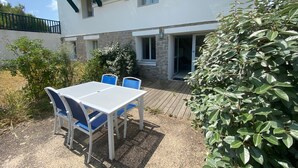 A patio with a table and chairs, a stone building with a balcony, and a garden area. - Batz-sur-Mer: Duplex Apt 2 Bedrooms, 6 Guests, Parking (Batz-sur-Mer)