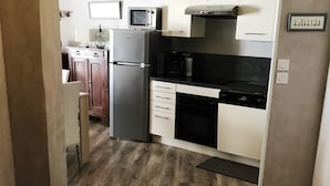 Eine kleine Küche mit Kühlschrank, Mikrowelle, Backofen und Geschirrspüler.