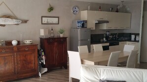 Eine moderne Küche mit weißen Schränken, einem Kühlschrank und einem Essbereich mit Tisch und Stühlen.
