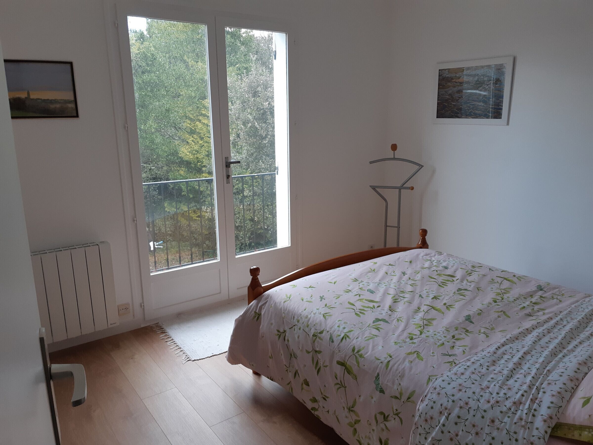 Un dormitorio con cama, radiador, ventana y puerta.