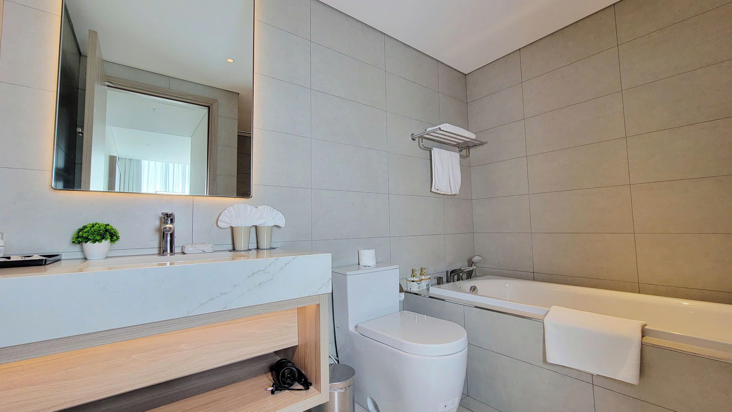 Et moderne badeværelse med et stort spejl, toilet, badekar og håndvask.