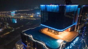 A modern hotel with a rooftop pool and a view of a river at night. - HB serviced Apartment - Ha Long (Bai Chay)