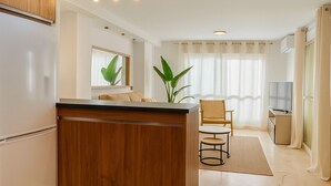 A modern kitchen with a wooden island, a dining area with a chair, and a TV. - Charming Maite apartment by the sea with terrace (Estepona)