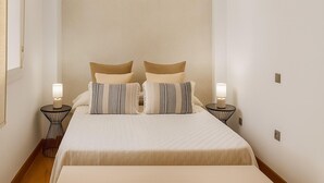 A neatly arranged bedroom with a bed, two bedside tables, and a hanging light fixture. - Charming Maite apartment by the sea with terrace (Estepona)