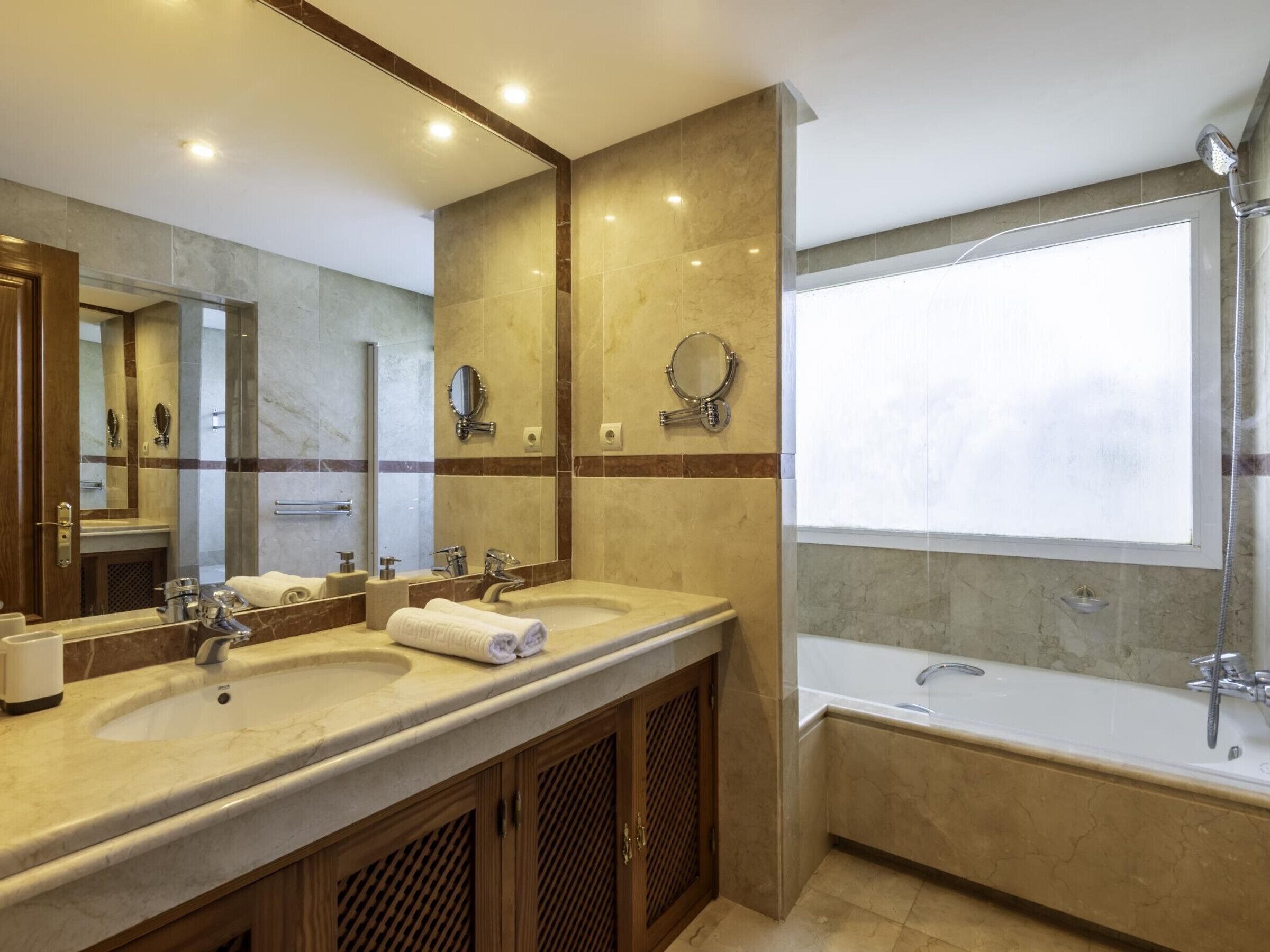 Een moderne badkamer met twee wasbakken, een grote spiegel en een bad.