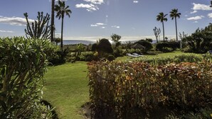A well-maintained garden with a variety of plants, including palm trees and succulents, and a clear view of the ocean. - Luxury beachfront apartment in Estepona (Estepona)