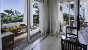 A spacious balcony with a view of a garden and palm trees, a sliding glass door, and a seating area with a bench and chairs. - Luxury beachfront apartment in Estepona (Estepona)