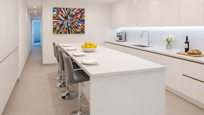 Una cocina moderna con una isla central, taburetes de bar, una cafetera y un lavaplatos.