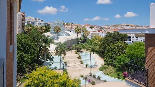 Vista de un resort con piscina, palmeras y un edificio de forma abovedada.