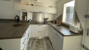 A modern kitchen with white cabinets, a built-in dishwasher, and a window providing natural light.