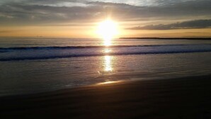 A beach with the sun setting over the horizon, creating a calm and serene atmosphere.