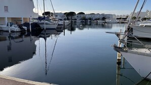 A marina with boats docked, calm water, and a building with a flat roof.